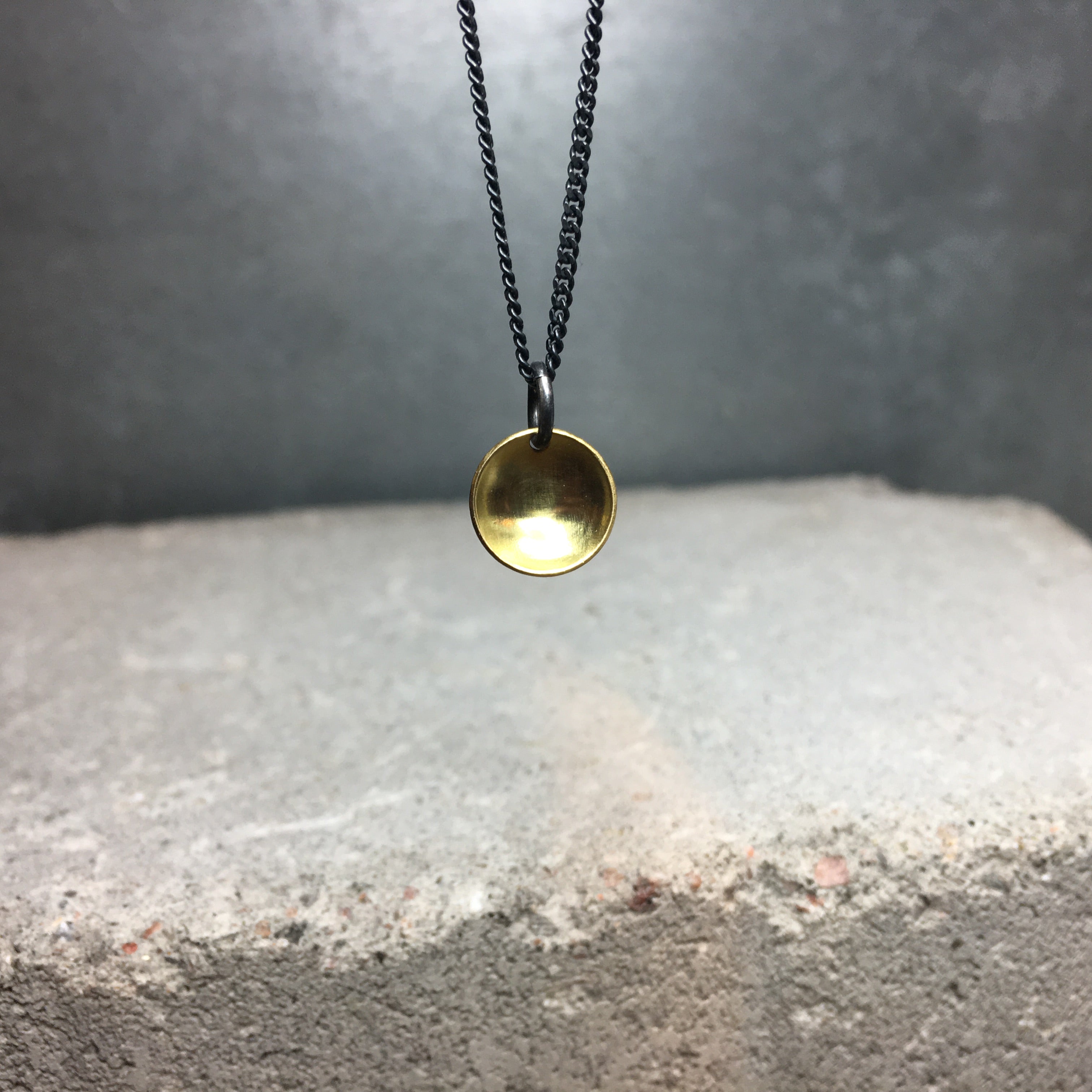 https://wildandarrow.com/cdn/shop/products/Dome_pendant_small_golden_brass_round_necklace_with_dark_silver_chain_made_by_wild-and-arrow_stockholm_sweden.jpg?v=1516464538